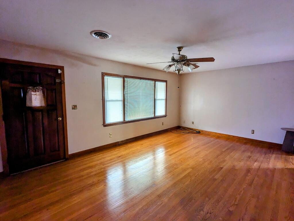 714 Glendale Road Galax, VA 24333 - Photo 8 of 26 an empty room with wooden floor chandelier fan and windows