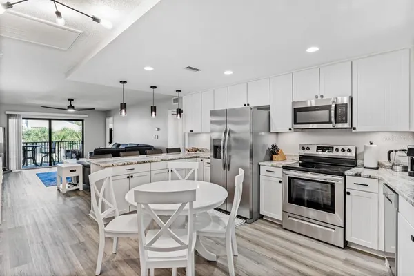 a kitchen with a refrigerator a stove top oven a sink dishwasher a dining table and chairs with wooden floor