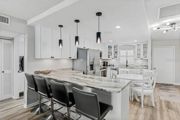 a kitchen with stainless steel appliances kitchen island a table chairs sink and cabinets
