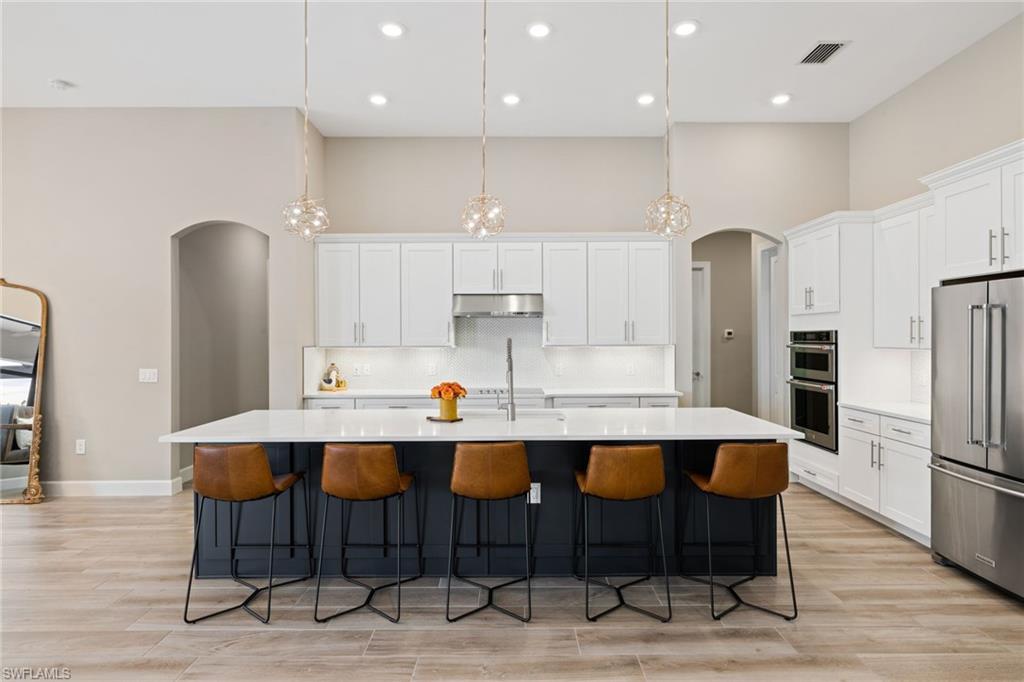 19134 Elston Way Estero, FL 33928 - Photo 11 of 35 a kitchen with a dining table chairs refrigerator and microwave