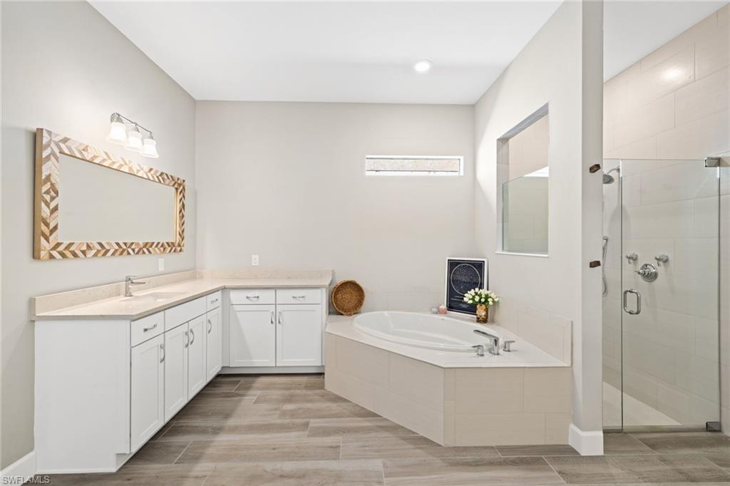 19134 Elston Way Estero, FL 33928 - Photo 24 of 35 a bathroom with a tub a sink and mirror