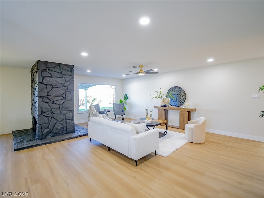 321 Lakehurst Road Las Vegas, NV 89145 - Photo 7 of 33 A floor-to-ceiling stone fireplace anchors the open living space above light vinyl plank flooring.