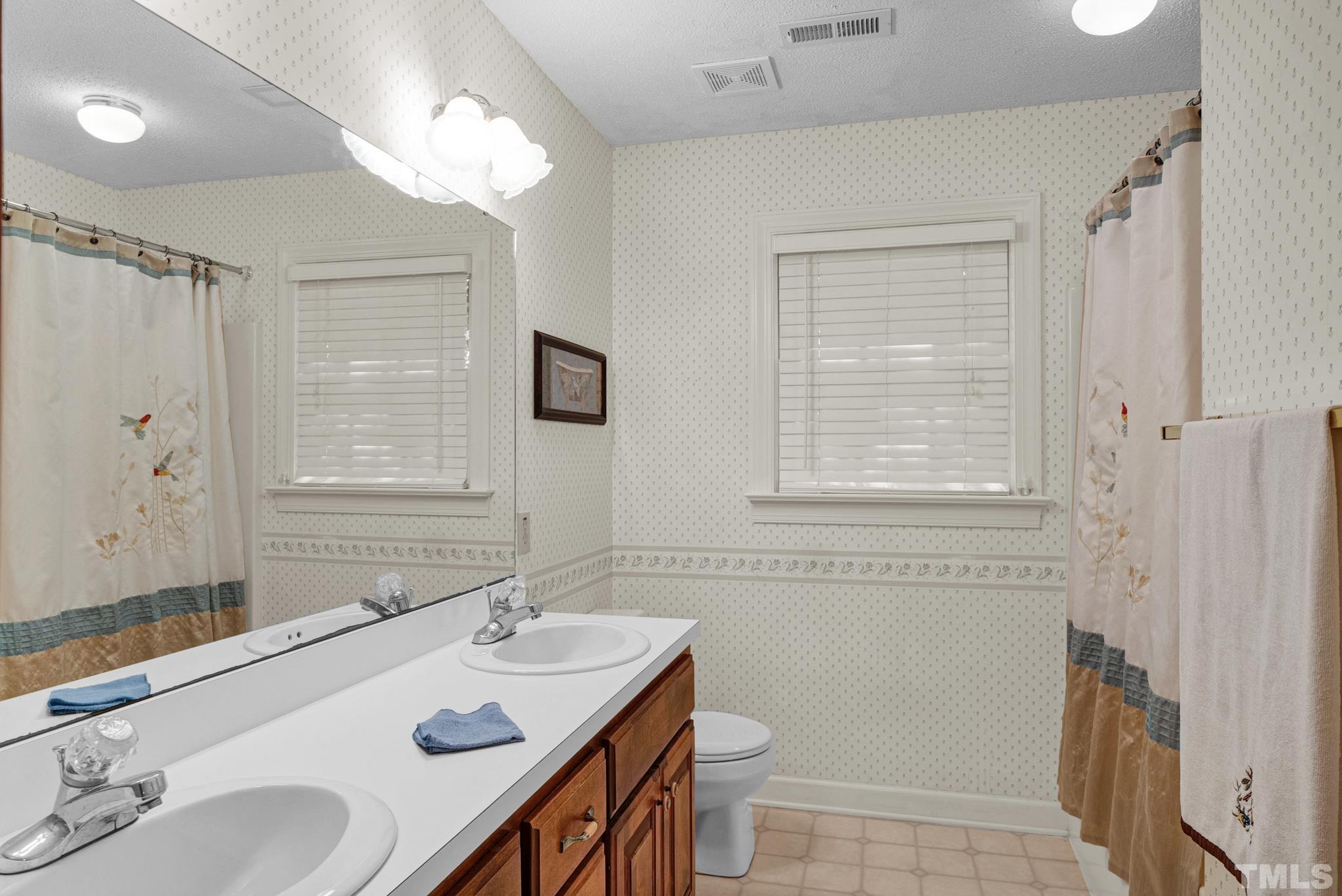 6408 Hampton Ridge Road Raleigh, NC 27603 - Photo 42 of 44 a bathroom with a sink double vanity granite tub shower and a mirror