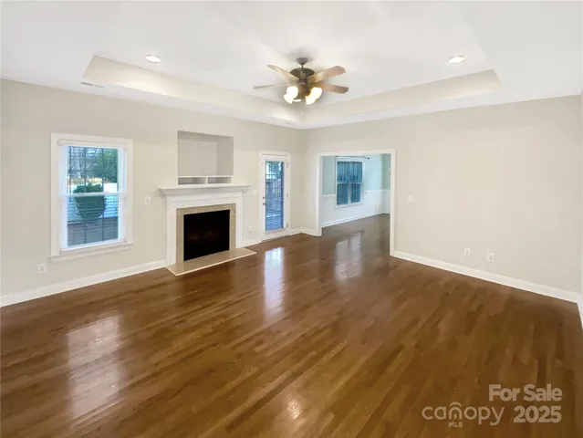 a view of an empty room with wooden floor and a fireplace
