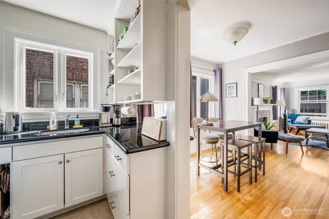 a kitchen with stainless steel appliances granite countertop a stove a sink dishwasher and white cabinets with wooden floor