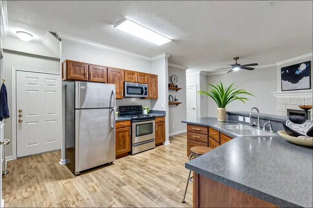 a kitchen with stainless steel appliances granite countertop a refrigerator a stove and a wooden floors