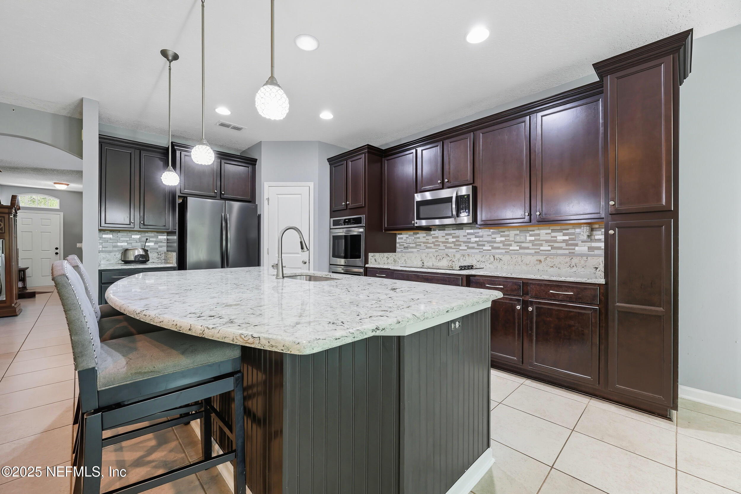 1218 Wetland Ridge Circle Middleburg, FL 32068 - Photo 19 of 75 a kitchen with kitchen island a counter space dining table and stainless steel appliances