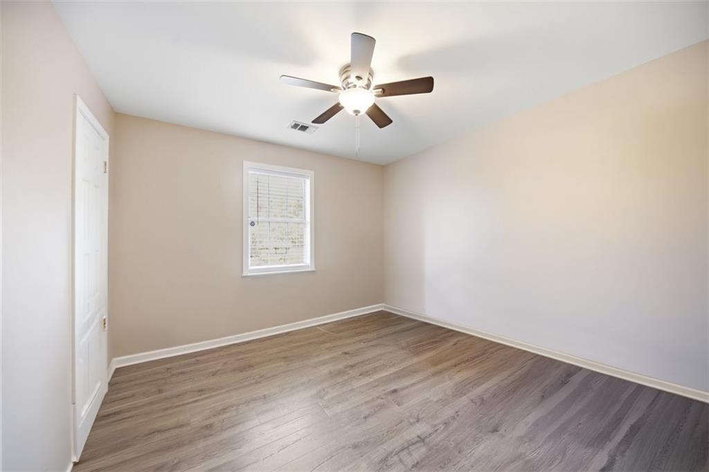 10 Stoneview Circle Covington, GA 30016 - Photo 15 of 25 an empty room with wooden floor ceiling fan and windows
