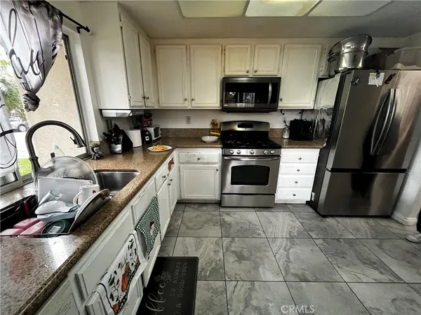 a kitchen with stainless steel appliances granite countertop a stove a sink dishwasher a refrigerator and a microwave