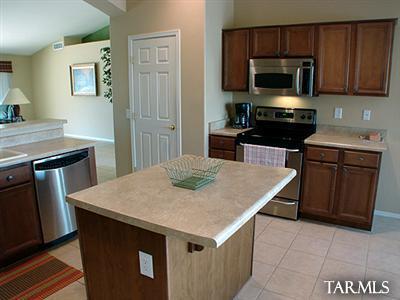 62195 East Northwood Road Tucson, AZ 85739 - Photo 12 of 25 a kitchen with a stove a microwave a sink a refrigerator and wooden cabinets