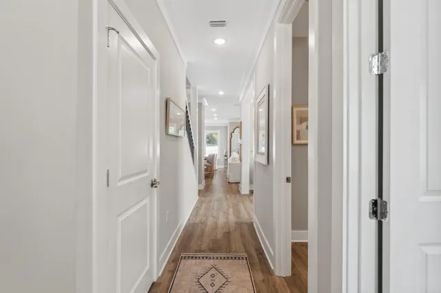 a view of a hallway with wooden floor and a bathroom