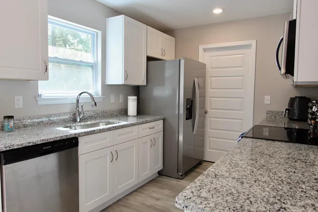 a kitchen with stainless steel appliances granite countertop a sink stove and refrigerator