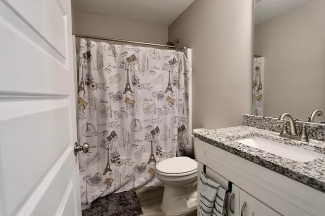 a bathroom with a granite countertop toilet a sink and a shower