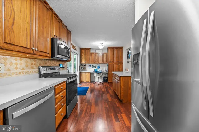 a kitchen with stainless steel appliances granite countertop a refrigerator a stove and a wooden floors