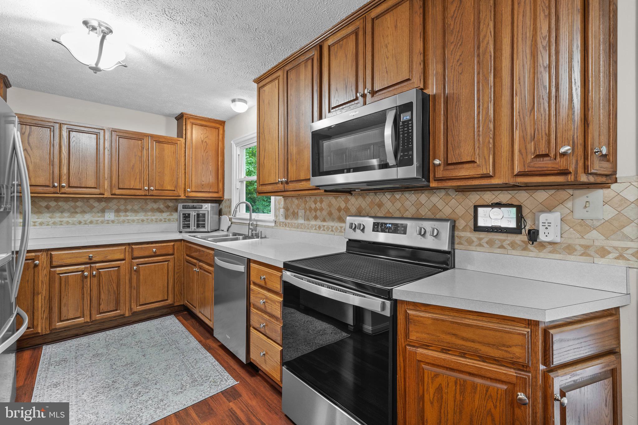 26599 Yowaiski Mill Road Mechanicsville, MD 20659 - Photo 23 of 58 a kitchen with granite countertop a stove top oven microwave and cabinets