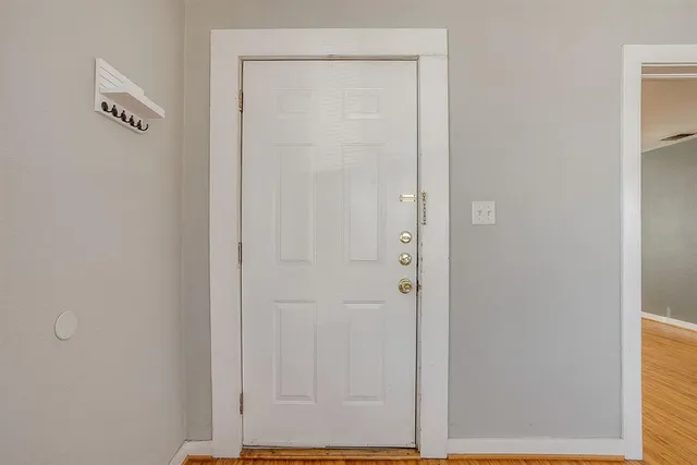 an empty room with wooden floor chandelier fan and windows