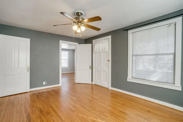 a view of an empty room with a window and wooden floor