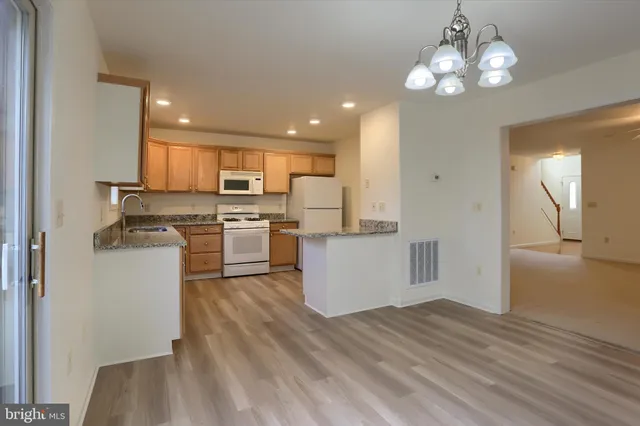 a kitchen with a refrigerator a stove top oven a sink dishwasher and wooden cabinets
