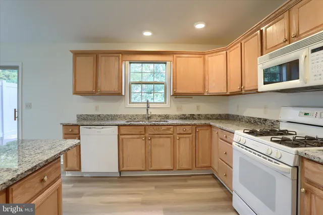 a kitchen with granite countertop cabinets stainless steel appliances a sink and a window