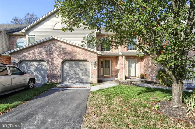 a view of a white house with a large tree and many windows
