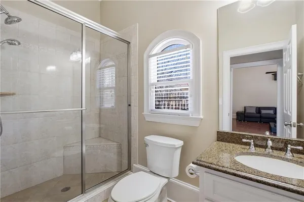 a bathroom with a granite countertop sink toilet a mirror a vanity and shower