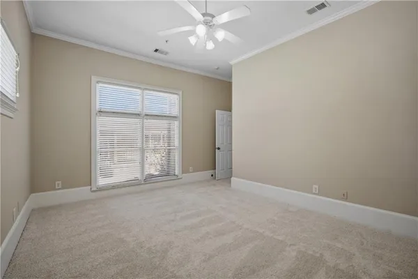 an empty room with chandelier fan and windows