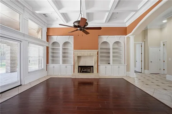 a view of a livingroom with wooden floor a fireplace window and a kitchen space