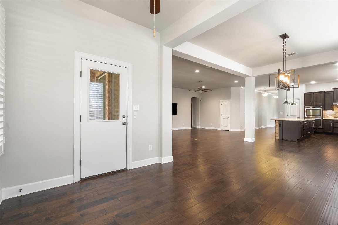 103 Lockhart Loop Georgetown, TX 78628 - Photo 18 of 40 Unfurnished living room with baseboards, dark wood finished floors, ceiling fan with notable chandelier, and visible vents