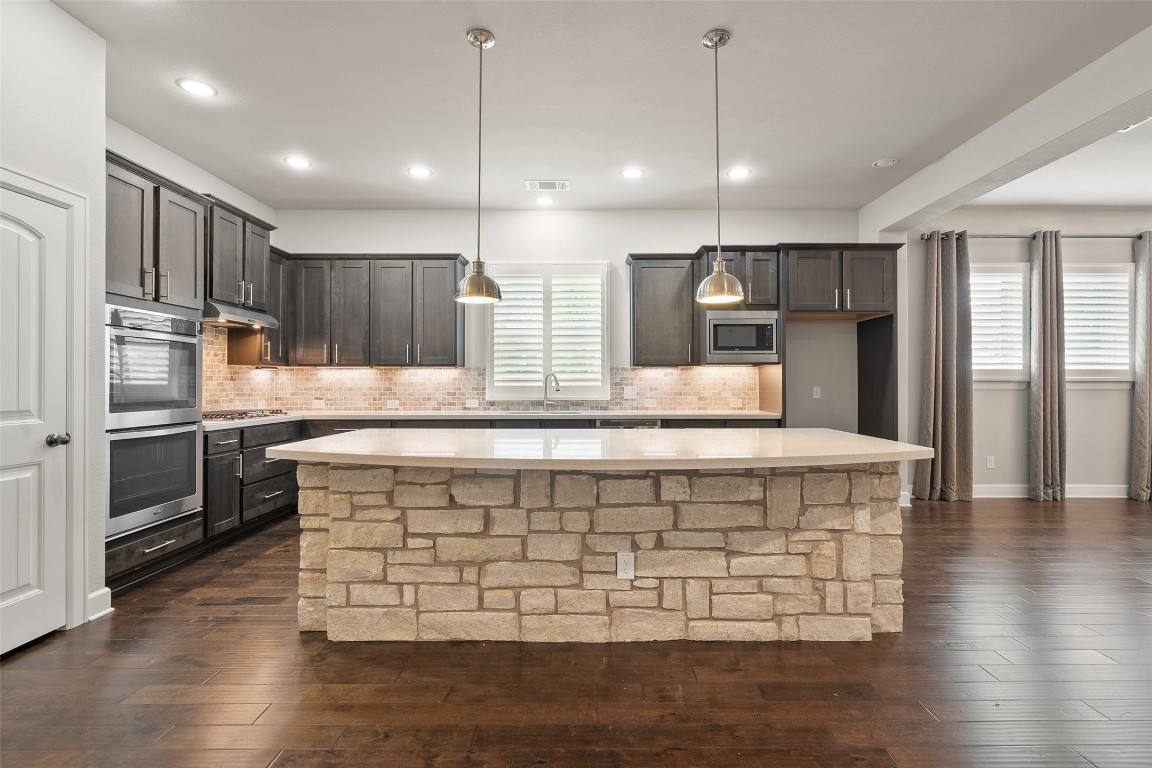 103 Lockhart Loop Georgetown, TX 78628 - Photo 5 of 40 a large kitchen with kitchen island a large counter top stainless steel appliances and cabinets