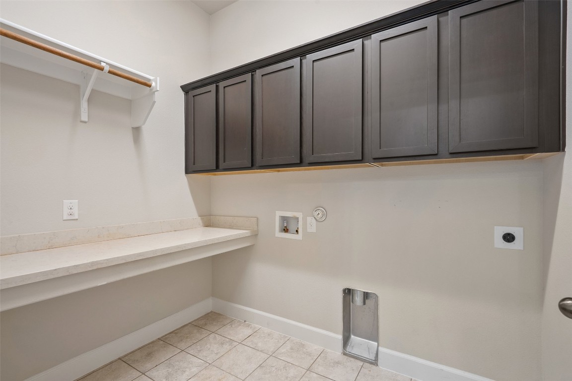 103 Lockhart Loop Georgetown, TX 78628 - Photo 10 of 40 Clothes washing area with baseboards, cabinet space, washer hookup, light tile patterned floors, and hookup for an electric dryer