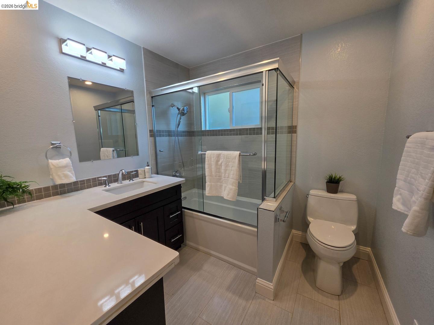 965 Springer Road Los Altos, CA 94024 - Photo 27 of 31 Modern bathroom featuring a dark wood-finish vanity with an integrated sink, a light-toned countertop, and a tiled backsplash