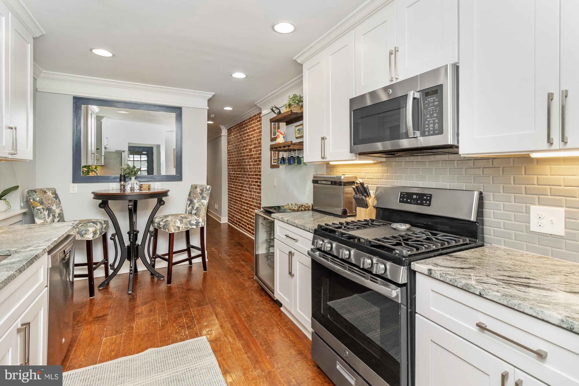 217 East Cross Street Baltimore, MD 21230 - Photo 13 of 50 a kitchen with stainless steel appliances granite countertop a stove top oven a sink dishwasher a dining table and chairs with wooden floor