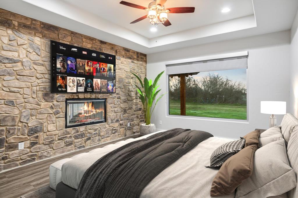 280 P East P Dawson Road, Unit E Maypearl, TX 76064 - Photo 5 of 11 Bedroom featuring a stone fireplace, a tray ceiling, and a ceiling fan