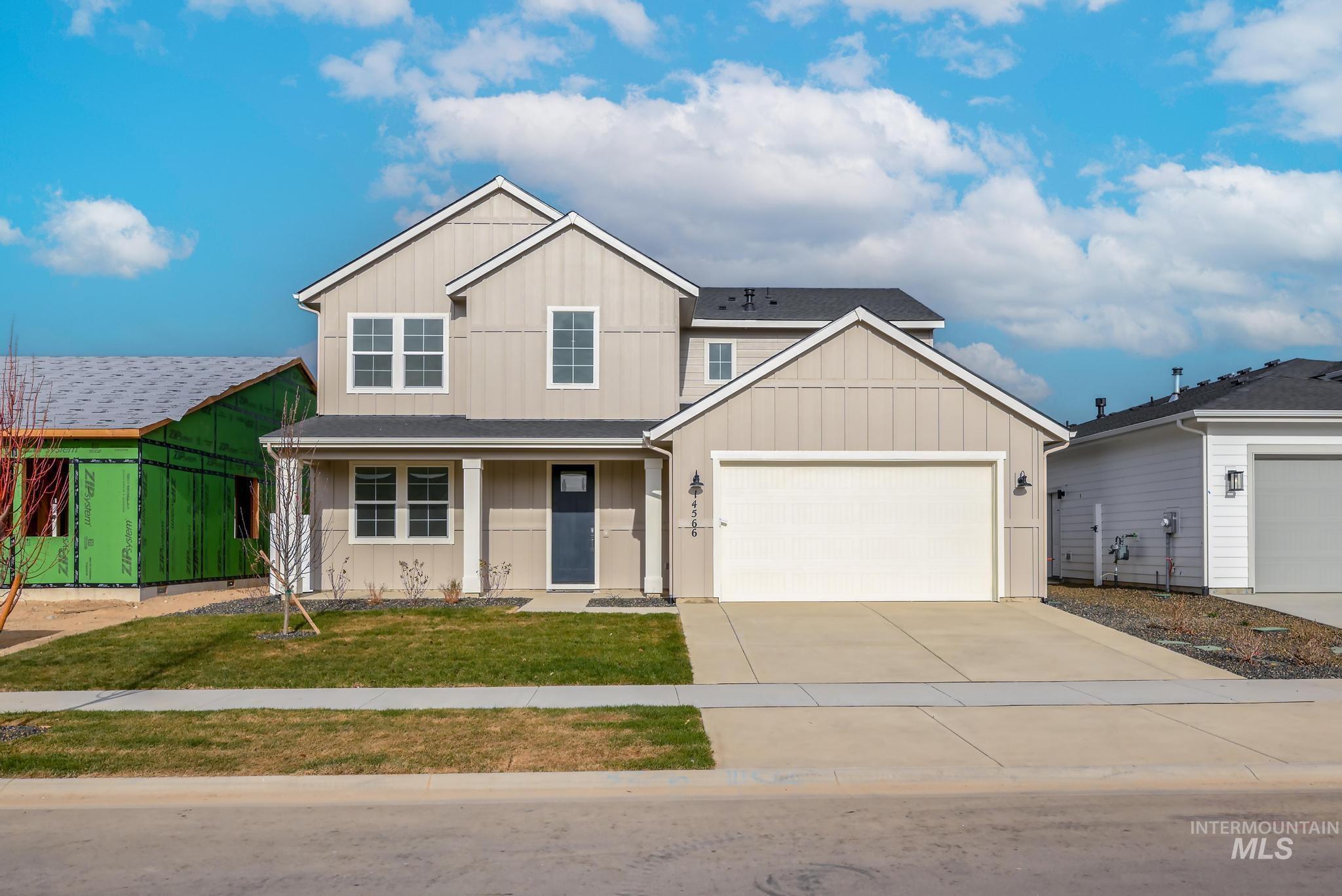 View of front of house featuring board and batten siding, a porch, concrete driveway, and a front lawn