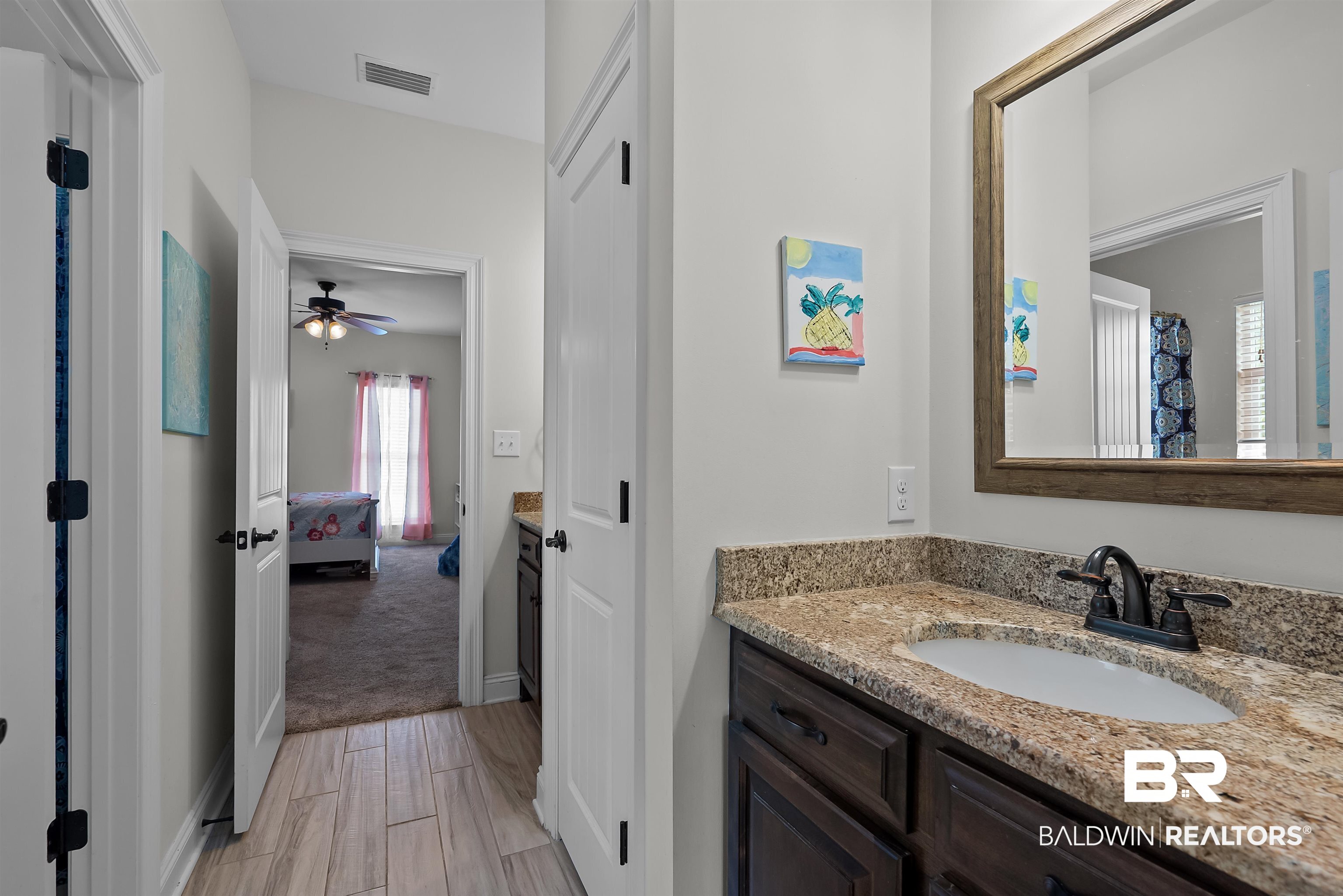 12070 Comalander Road Fairhope, AL 36532 - Photo 31 of 50 Bathroom vanity featuring a granite countertop, undermount sink, and dark wood-finish cabinetry
