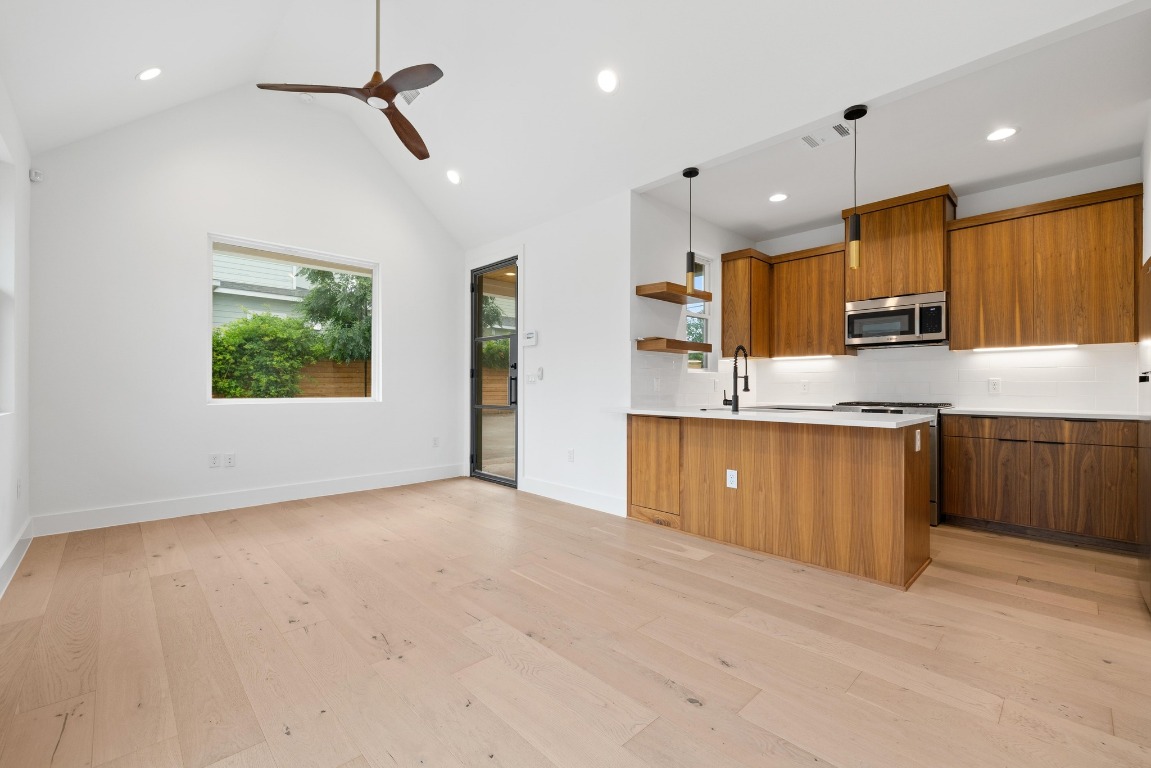 a large kitchen with kitchen island a sink dishwasher a stove and a refrigerator with wooden floor