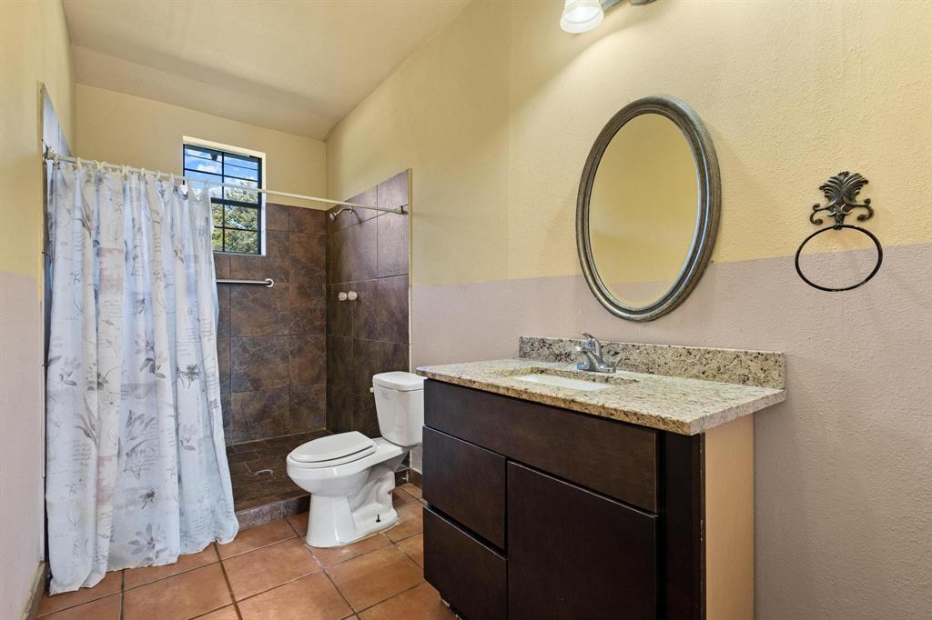 5777 State Highway 160 Whitewright, TX 75491 - Photo 21 of 36 a bathroom with a granite countertop sink a toilet and a mirror