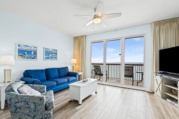 a living room with furniture a flat screen tv and a ceiling fan