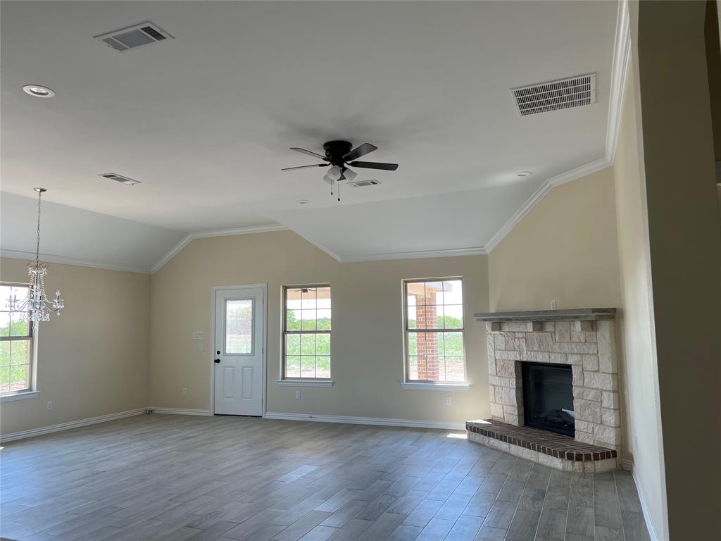 8008 County Road 1058 Rice, TX 75155 - Photo 5 of 25 Spacious room featuring vaulted ceilings with crown molding, wood-finish flooring, a stone fireplace with a brick hearth, and multiple windows