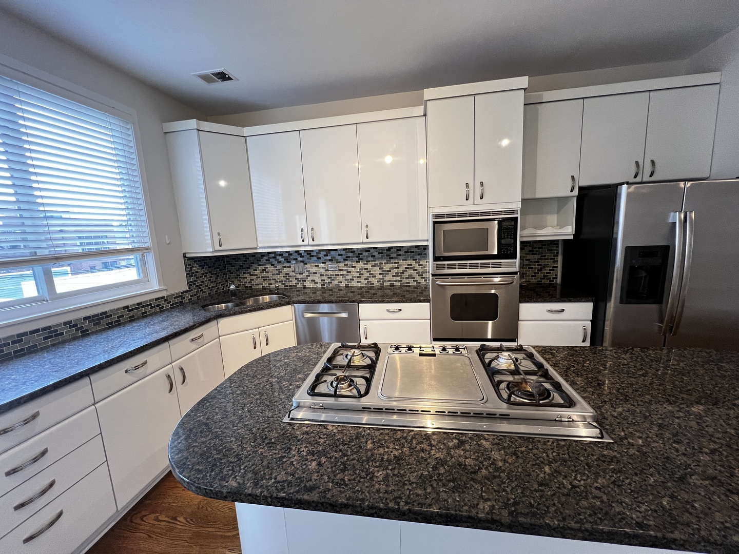Undisclosed Address Chicago, IL 60657 - Photo 3 of 25 a kitchen with kitchen island granite countertop a stove a sink and a microwave