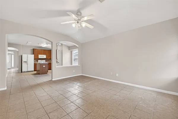 a view of an empty room with a chandelier fan and windows
