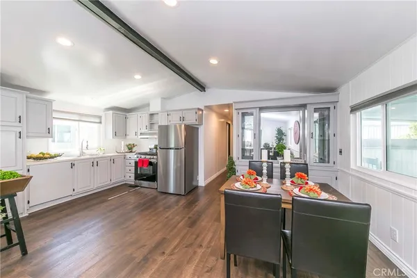 a living room with furniture dining table a refrigerator and wooden floor