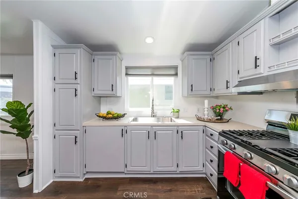 a kitchen with granite countertop a sink a stove and cabinets
