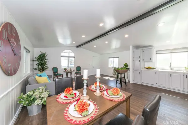 a dining room with furniture a potted plant and open kitchen view