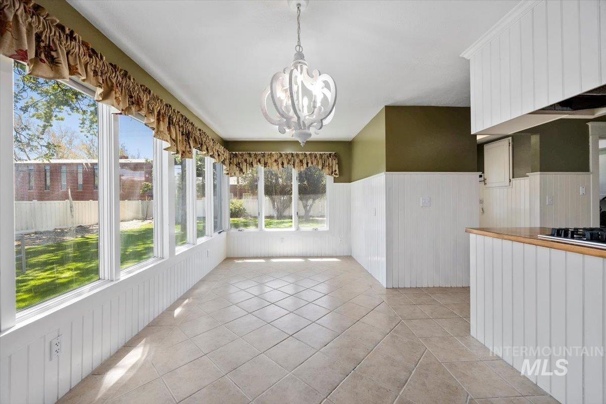 813 7th Street Rupert, ID 83350 - Photo 25 of 48 Sunroom with multiple windows, ceramic tile flooring, beadboard wainscoting, and a decorative ceiling light fixture