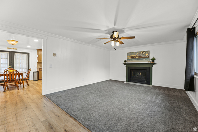 822 Pinewood Circle Price, UT 84501 - Photo 3 of 49 Spacious living area featuring a central fireplace with a dark mantel, crown molding, and a ceiling fan