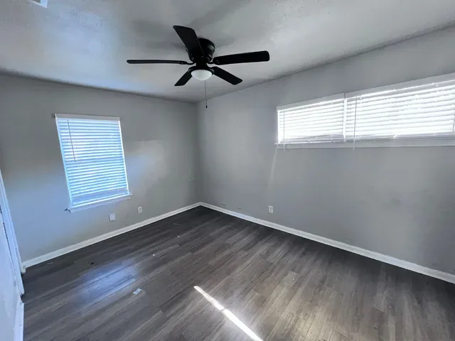 a view of empty room with wooden floor and fan