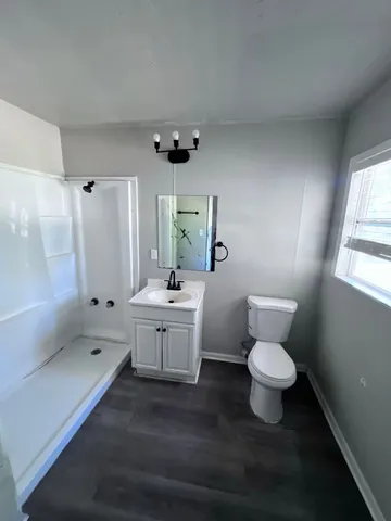 a bathroom with a toilet sink a mirror and a shower