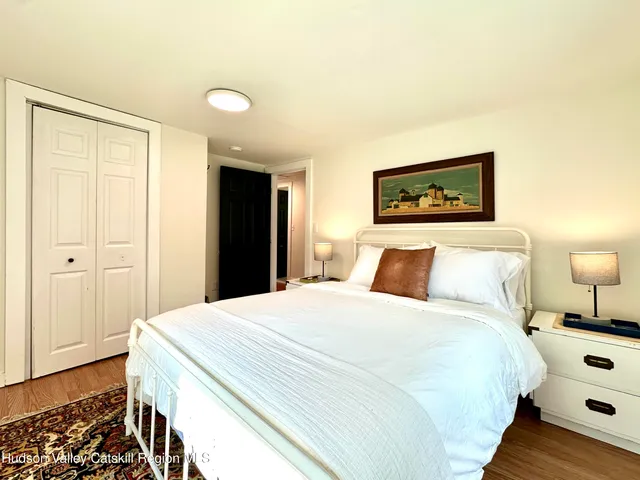 a spacious bedroom with a bed and a lamp on dresser