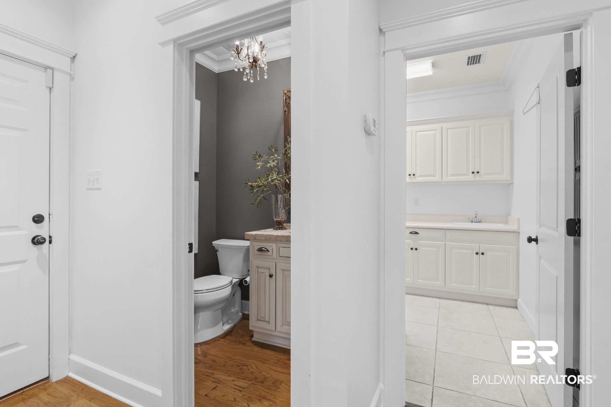 11261 Halcyon Loop Daphne, AL 36526 - Photo 27 of 41 Hallway featuring a powder room with a vanity and a utility room with built-in cabinetry, a countertop, and a sink